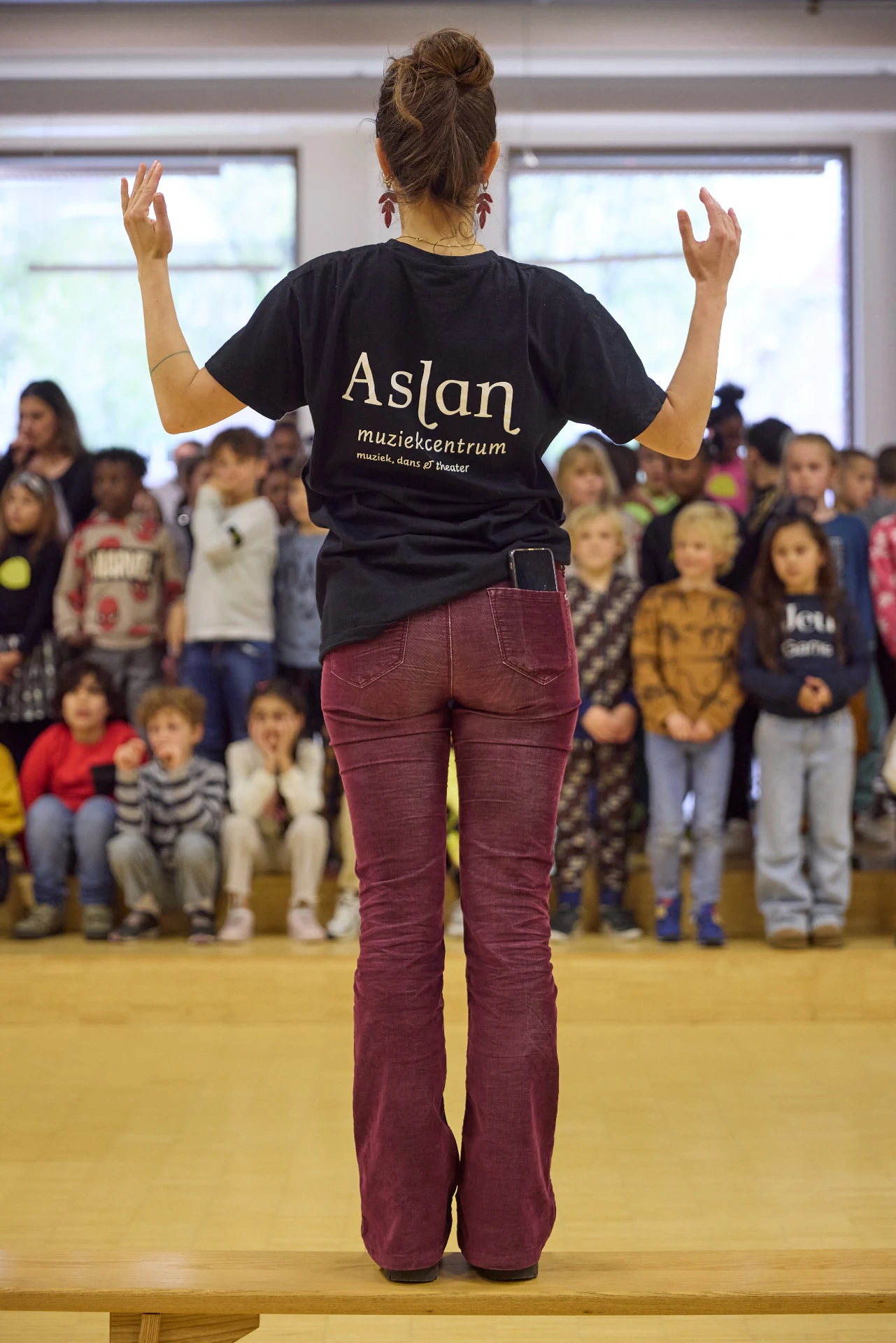 Docent van Aslan dirigeert een schoolplein vol leerlingen tijdens Opera in de klas