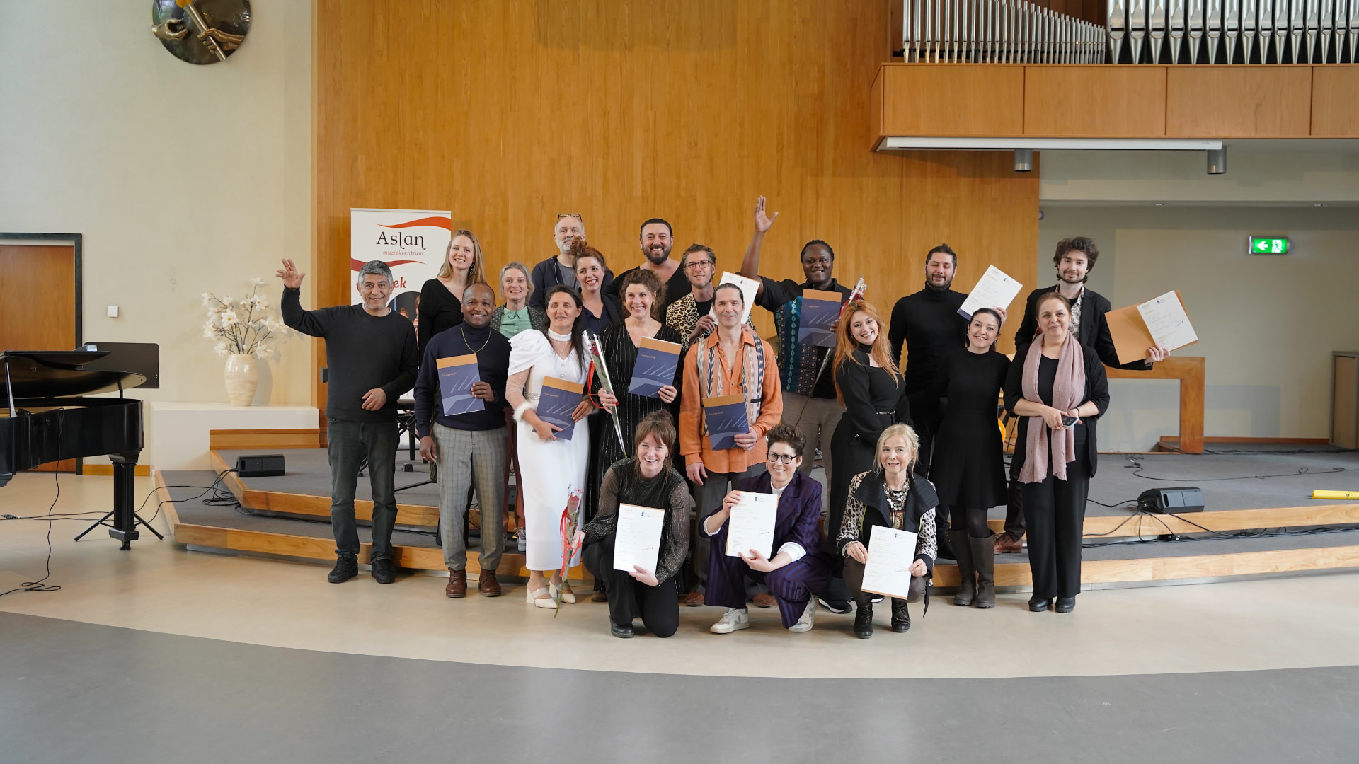 Groepsfoto van geslaagden van de Aslan Opleiding Muziekeducatie met hun diploma in de hand