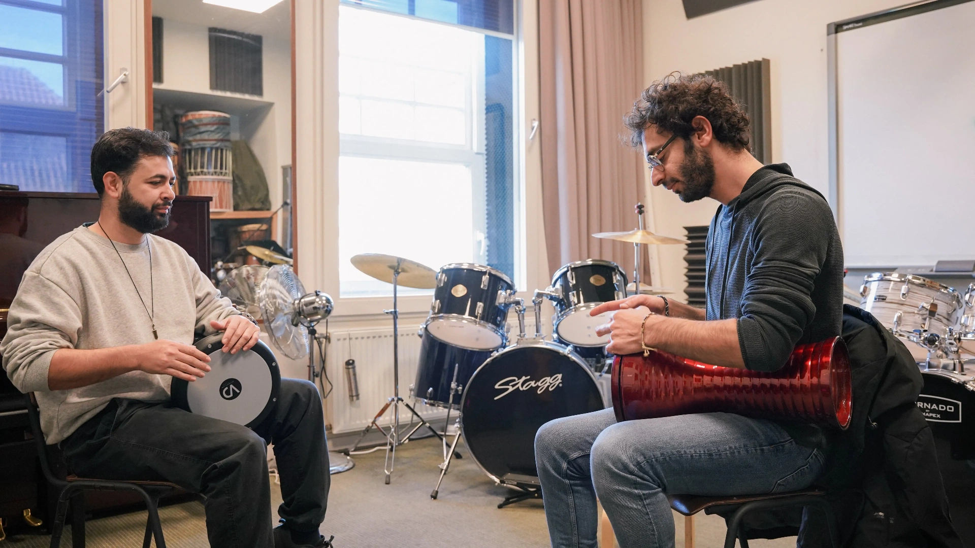 Twee percussionisten oefenen samen op handpercussie tijdens een Aslan-training
