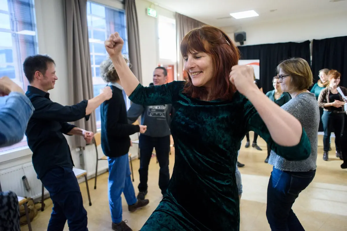 Deelnemers van een Aslan-training dansen energiek tijdens een workshop